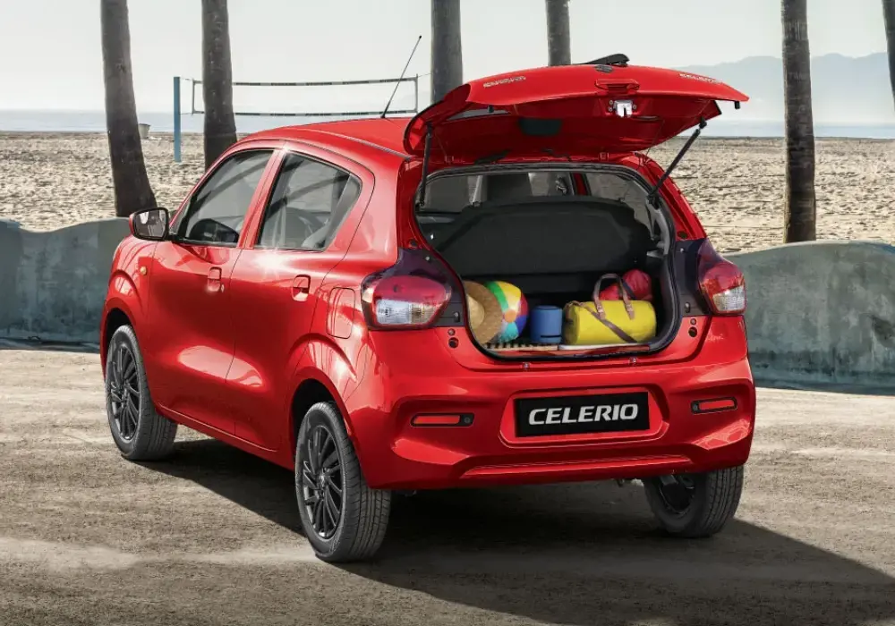 Vista trasera de un Suzuki Celerio rojo brillante estacionado en un entorno de playa