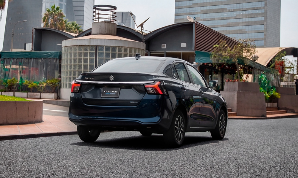 Vista trasera de sedán Suzuki Dzire siendo conducido por la ciudad